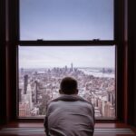 man in gray shirt looking at city buildings during daytime