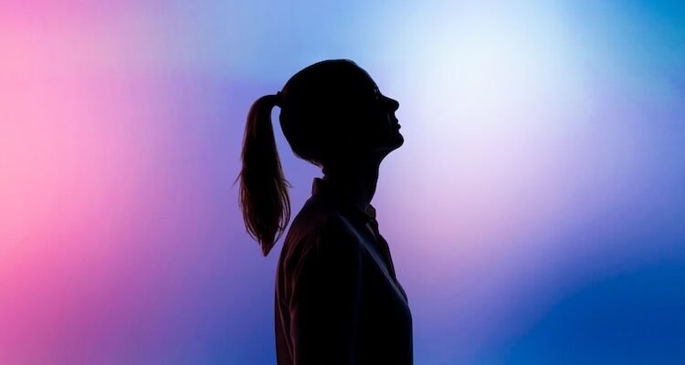 silhouette of woman wearing black hat and black coat
